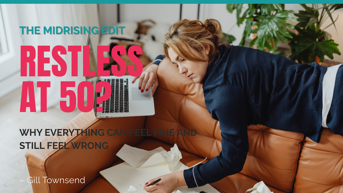 Woman sprawled across a sofa with a laptop and notebook, looking exhausted. Midrising Edit cover: “Restless at 50? Why Everything Can Feel Fine and Still Feel Wrong.”